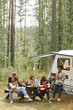 © Seventyfour - Vertical wide angle view at diverse group of young people enjoying picnic outdoors while camping with trailer van, copy space