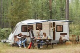 Fototapeta  - Wide angle view of young people enjoying outdoors while camping with van in forest, copy space