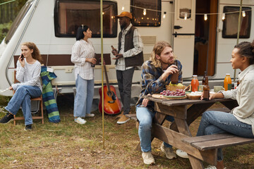 Wall Mural - Diverse group of young people relaxing outdoors while camping with van in forest, copy space