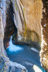 Deep canyon with waterfall coming from mysterious cave opening