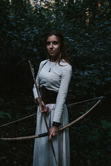 girl in a historical dress in a coniferous forest