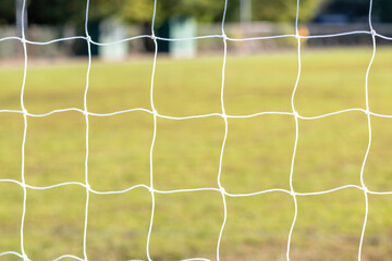 Wall Mural - Football game arena through soccer nets. Blurred background.