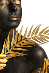 Beautiful young woman with  black and golden paint on her body and tropical leaf against white background