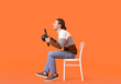 © Pixel-Shot - Young man with steering wheel sitting on chair against color background