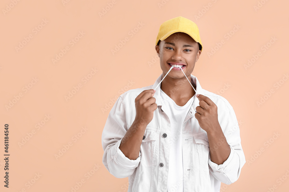 Young African-American guy with chewing gum on color background