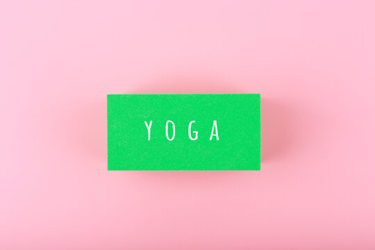Single word yoga written on green rectangle on bright pink background