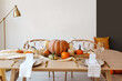 © Pixel-Shot - Dining table with pumpkins near light wall