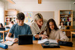 © Maskot - Female teacher teaching teenage girl on book in classroom