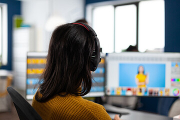 Creative photographer editor retouching photos of a client on performance PC with two displays setup. Woman retoucher working in editing software app sitting office holding stylus pen