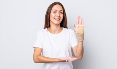 Poster - young pretty woman smiling cheerfully, feeling happy and showing a concept. hand bandage concept