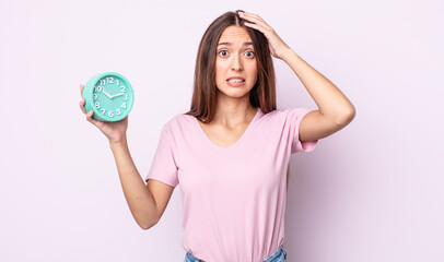 Poster - young pretty woman feeling stressed, anxious or scared, with hands on head. alarm clock concept