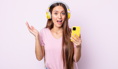 Wall Mural - young pretty woman feeling happy and astonished at something unbelievable. headphones and smartphone