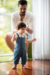 © chokniti - father help children baby to walk, childhood family people with little cute toddler child son, happy learning in first step with support together from father at home