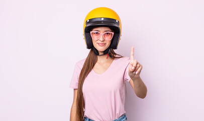 Poster - young pretty woman smiling and looking friendly, showing number one. motorbike rider and helmet