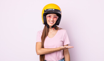 Poster - young pretty woman smiling cheerfully, feeling happy and showing a concept. motorbike rider and helmet