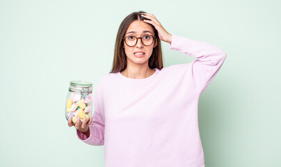 Poster - young pretty woman feeling stressed, anxious or scared, with hands on head. jelly candies concept