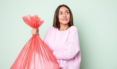 Poster - young pretty woman shrugging, feeling confused and uncertain. trash concept