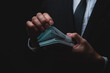 Closeup of hands of a young male businessman and entrepreneur wearing formal clothing in suit and tie holding and counting cash paper money