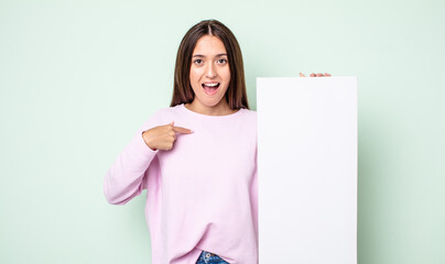 Poster - young pretty woman feeling happy and pointing to self with an excited. empty canvas concept