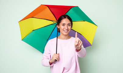 Poster - young pretty woman smiling and looking friendly, showing number one. umbrella concept