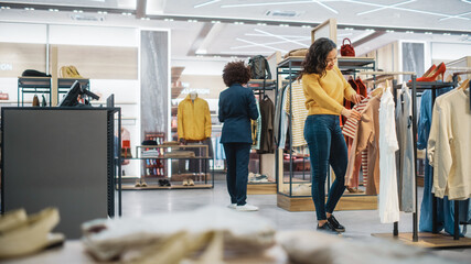 Wall Mural - Beautiful Smiling Female Customer Shopping in Clothing Store, Choosing Stylish Clothes, Picking Dress, Blouse. People in Fashionable Shop, Colorful Brand, Sustainable Designs, New Seasonal Collection.