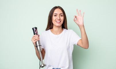 Poster - young pretty woman feeling happy, showing approval with okay gesture. hand mixer concept