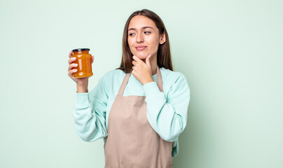 Poster - young pretty woman smiling with a happy, confident expression with hand on chin. peach jelly concept