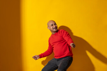 Wall Mural - Portrait of a bald man dancing against plain background.