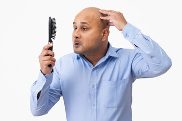 Wall Mural - Portrait of a bald man touching his shaved head while looking sadly at comb in his hand.