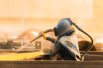 Sand blasting process, Industial worker using sand blasting process preparation cleaning surface on steel before painting in factory workshop.