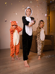 Wall Mural - Three children in funny rompers releasing Christmas cracker at home party	