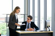 © chadchai - Teenager employee hand over quarter's sales report to colleague.  Morning work atmosphere in a modern office.
