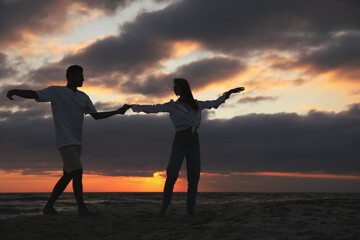 Poster - Happy couple dancing on beach at sunset