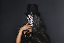 Female Model In Halloween Silence. Sexy Brunette Woman In Skull Makeup And Latex Costume On Black Background. Halloween Costume Concept.