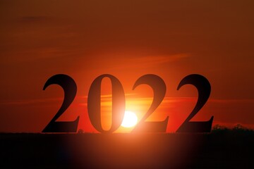 Wall Mural - Happy New year 2022 with large silhouette letters on the mountain with sunset light,