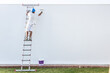 © ADDICTIVE STOCK - Back view of a young painter painting on a ladder