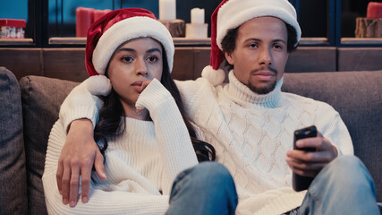 Wall Mural - African american man watching movie with girlfriend in santa hat