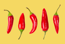 Set of red hot chili peppers on yellow isolated, closeup.