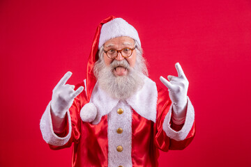 Santa Claus making rock n roll sign with hands and red background.