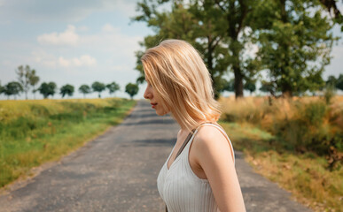 Poster - Woman with blond hair and white clothes stay on country road