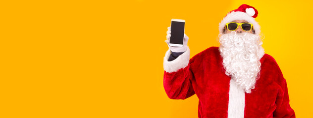 Wall Mural - santa claus showing mobile phone with space for copy