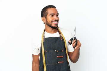 Poster - Young Ecuadorian design man holding scissors isolated on white background looking to the side and smiling