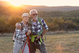 Fototapeta  - Couple of mature people smile and rest afther walking in nature with sunset on background