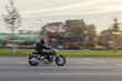 © Armands photography - A motorcycle rides on the street at high speed in front of the rising sun. The motorcyclist dressed in all black. Motion blur