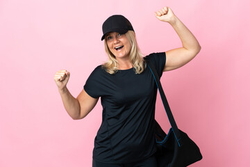 Wall Mural - Middle age woman with sport bag isolated on pink background celebrating a victory