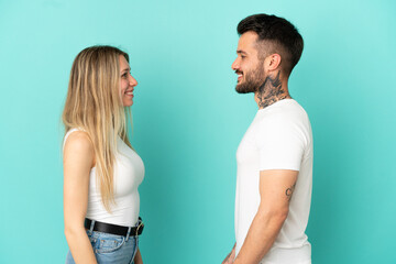 Wall Mural - Young couple over isolated blue background looking at each other