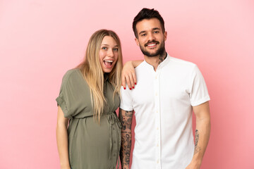 Wall Mural - Pregnant woman and man over isolated pink background happy and laughing