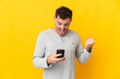 © luismolinero - Young caucasian handsome man isolated on yellow background surprised and sending a message