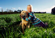 © SuperStock - Girl and golden labrador dog sitting in green field