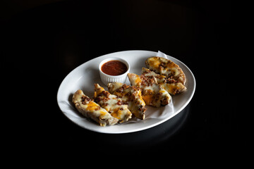 Sticker - Melted cheese and meat on bread slices on a plate with sauce isolated on a black background